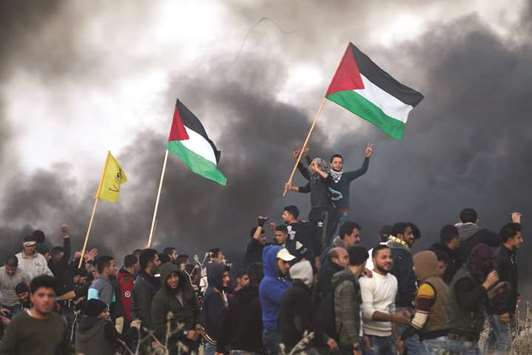 Palestinian protesters wave national flags during clashes with Israeli security forces on the eastern outskirts of Gaza City, yesterday.