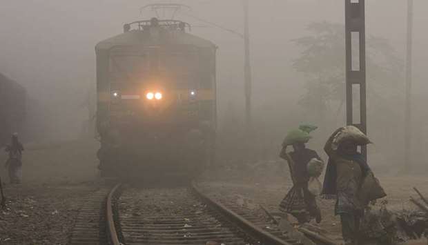 Women walk along a track as a train waits amid heavy fog and air pollution at Sahibabad station in Ghaziabad, some 25km east of New Delhi, yesterday.