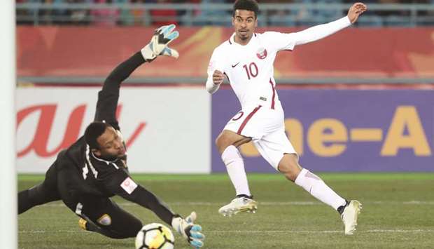 Qataru2019s Akram Afif scores past Oman goalkeeper  Ibrahim al-Mukhaini in Changzhou yesterday. At bottom, Afif is mobbed by teammates as they celebrate the goal.