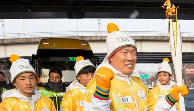 South Korean football legend Cha Bum-Kun (C) carries the Olympic flame during the PyeongChang 2018 Torch Relay near the World Cup Stadium in Seoul.