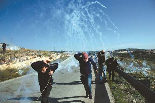 Palestinians run for cover from smoke-grenades during clashes with Israeli security forces following a demonstration in support of Palestinian prisoners yesterday, in the West Bank village of Nabi Saleh.
