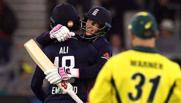 England batsman Joe Root (C) embraces teammate Moeen Ali (L) as Australia's David Warner (R) looks on after England defeated Australia in their one-day international cricket match played at the MCG in Melbourne