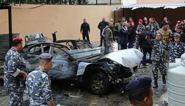 Lebanese security forces stand near a damaged vehicle following a car bomb blast in the southern Lebanese port city of Sidon.