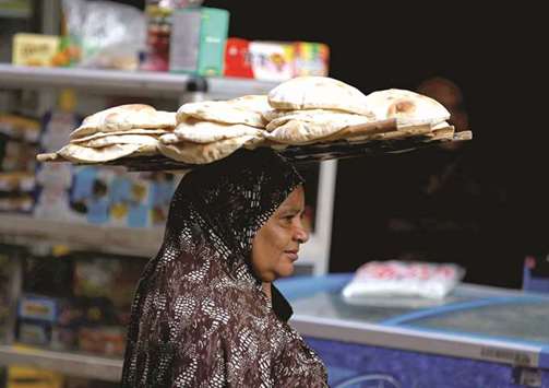A woman carries bread as she leaves a bakery in Cairo (file). Economists say the inflation drop in Egypt is the result of a strong base effect, and not necessarily a meaningful economic recovery.