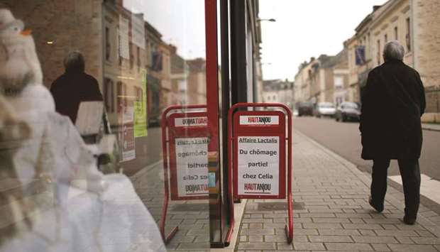 A man walks past a placard which reads u2018Lactalis affair, partial  unemployment at Celia factoryu2019, in Craon, western France.