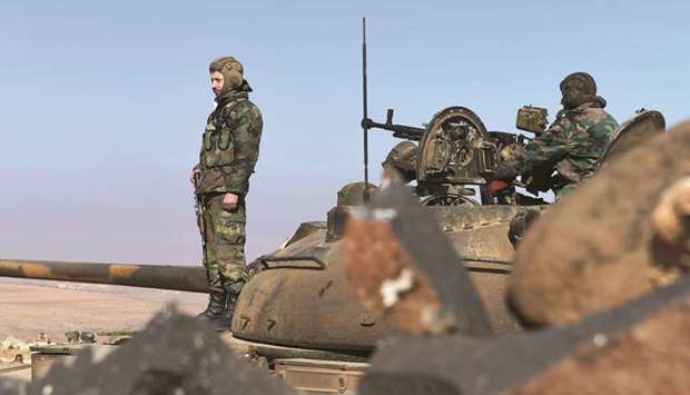 Members of the Syrian government forces stand on a tank in Jabal al-Hass in the southern part of Aleppo province as they advance towards the Abu Duhur military airport in the ongoing offensive against opposition fighters, yesterday.