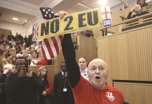 A demonstrator holds a pro-Brexit sign and a US flag, as the speech by the Mayor of London, Sadiq Khan, is interrupted at the Fabian Society New Year Conference, in central London on Saturday.
