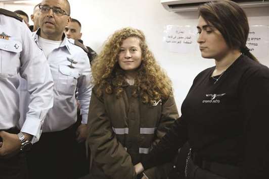 Palestinian teen Ahed Tamimi enters a military courtroom escorted by Israeli security personnel at Ofer Prison, near the West Bank city of Ramallah, yesterday.