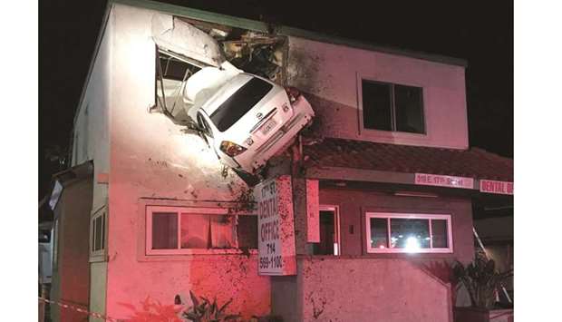 A car dangles off the second floor of a building after speeding into a median and going airborne in Santa Ana, California.
