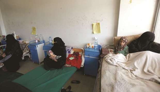Children sit with their mothers in beds at a hospital in Sanaa.