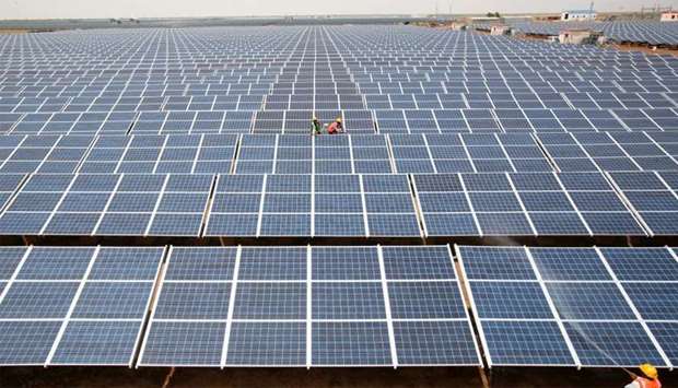 Workers install photovoltaic solar panels at the Gujarat solar park under construction in Charanka village
