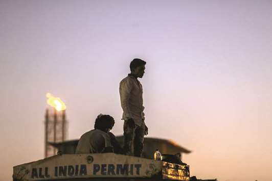 A man stands on the roof of a truck cab as a flame blazes from a gas flare stack at a Bharat Petroleum Corp refinery in the Mahul area of Mumbai (file). India is one of the worldu2019s fastest growing energy consumers and Prime Minister Narendra Modi is allowing investors the rare freedom of deciding the areas they want to drill in as he seeks to boost production and cut Indiau2019s oil imports by 10% by 2022.