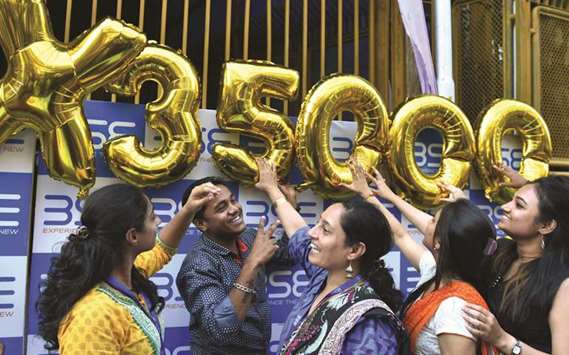 Indian workers pose outside the Bombay Stock Exchange during celebrations marking the benchmark 30-share index Sensex crossing 35,000 points in Mumbai yesterday.