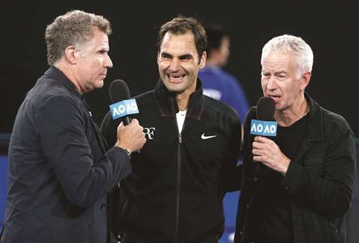 Roger Federer of Switzerland speaks with actor Will Ferrell (left) and retired tennis player John McEnroe (right) after winning his match against Aljaz Bedene of Slovenia on Tuesday. (Reuters)