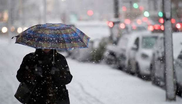 A woman uses an umbrella to protect herself against heavy snowfall in Hamburg on Thursday.
