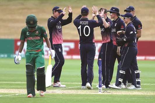 England players (in blue) celebrate the wicket of a Bangladeshi player (in green) during their match in Queenstown yesterday. (ICC)