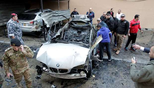 People inspect the car damaged in a bomb attack at Sidon in southern Lebanon on January 14, 2018