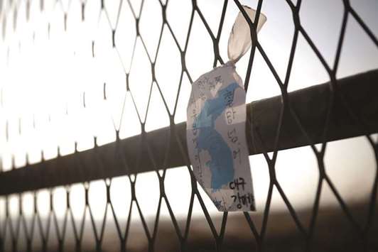 A unification flag hangs on a military fence near the demilitarized zone (DMZ) separating the two Koreas in Paju, South Korea, yesterday . The Korean characters read: u201cIu2019d like to walk freely beyond this military fence.u201d