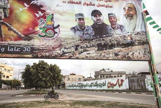 A Palestinian rides a motorcycle past a billboard bearing the portraits of the commanders of Hamasu2019 armed wing Al-Qassam Brigades, in Rafah in the southern Gaza Strip, yesterday. A family has said it had killed one of its members, after he was accused of aiding Israel in the killings of three Qassam commanders.