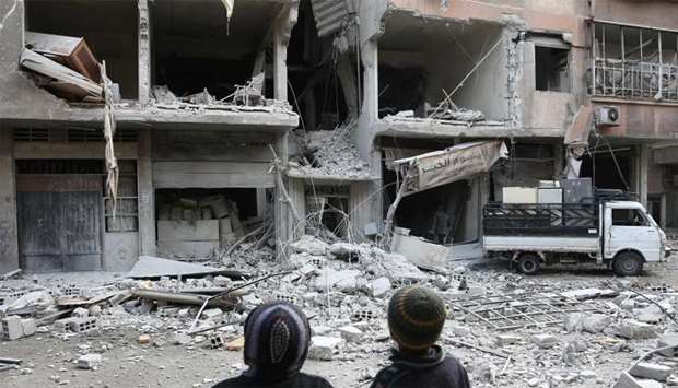 Syrian children look at a building that was damaged in a missile attack on the rebel-held besieged town of Arbin