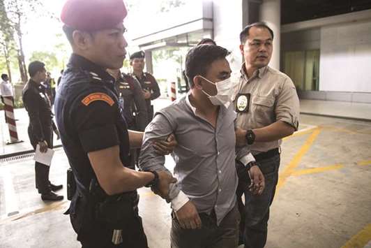 Boonchai Bach (centre), an alleged kingpin in Asiau2019s illegal trade in endangered species is handled by Thai policemen in Bangkok after his arrest, yesterday.