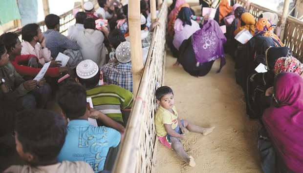 A Rohingya child sits on the floor while his mother waits in a queue to collect aid supplies in Kutupalong refugee camp in Coxu2019s Bazar, Bangladesh, yesterday.