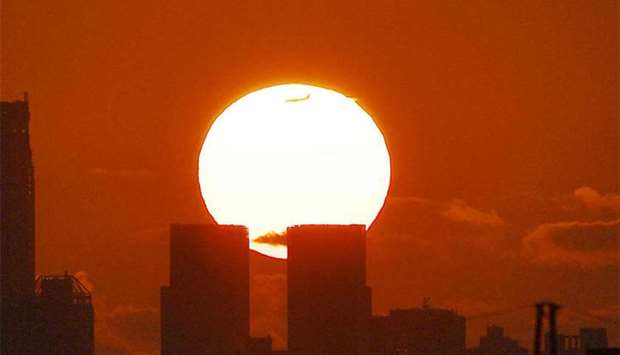 A plane flies past the setting sun behind the Manhattan skyline in New York. File photo: August 30, 2017
