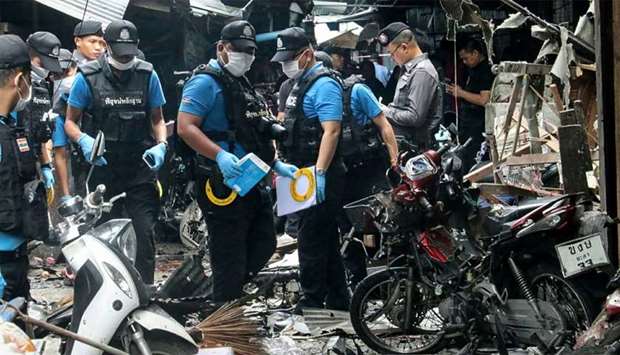 A Thai forensics unit scours the aftermath of a motorcycle bombing which killed three civilians and wounded others at a market in the southern Thai province of Yala