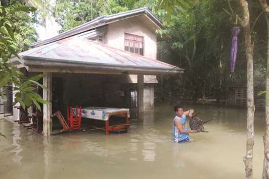 A resident gathers belongings from their flooded house after a tropical depression hit Loboc town, Bohol province, in the central Philippines, yesterday.