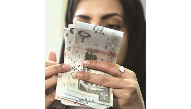 A Saudi woman counts riyal banknotes at a money exchange shop in Riyadh (file). Like in the UAE, Saudi Arabiau2019s insurance market remains largely fragmented, with 33 listed takaful operators competing against each other.