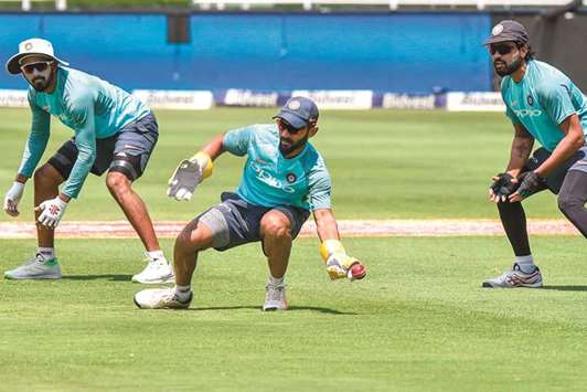 India's Dinesh Karthik (centre) dives to catch the ball as KL Rahul (left) and Murali Vijay look on during a training session on the eve of the third Test against South Africa in Johannesburg. (AFP)