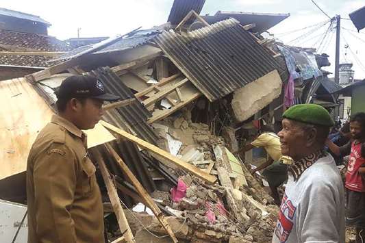 An official talks to a villager as he examines damage after an earthquake struck Kuta village in Bogor in West Java yesterday.