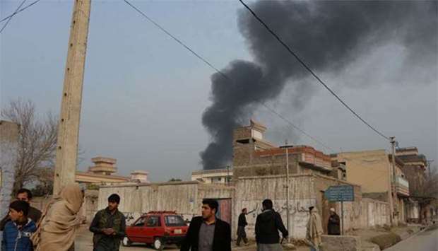 Afghan civilians gather on a street next to a plume of smoke coming from the area around an office of the British charity Save the Children during an attack in Jalalabad on Wednesday.