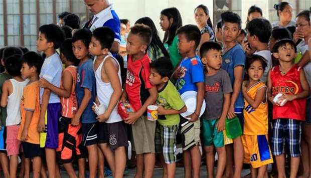 Children staying at a temporary evacuation centre queue for free snacks in Legazpi city, Albay province, on Thursday.