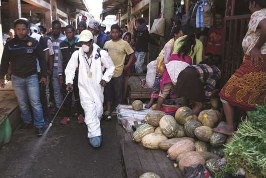 File photo shows people standing back as a council worker sprays disinfectant during the clean-up of the market in the Anosibe district, one of the most insalubrious districts of Antananarivo.