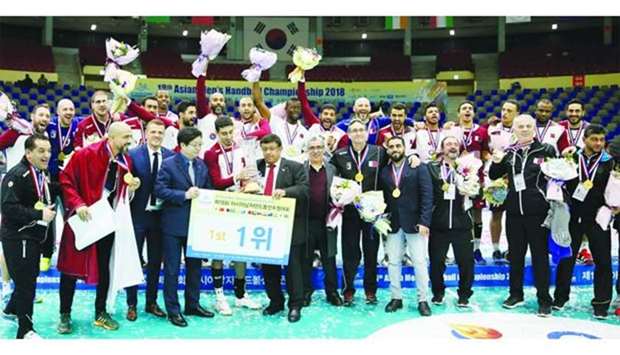 Qatar handball players and officials celebrate with the trophy.