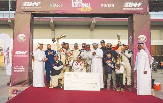 Qatar Baja winners pose with their trophies as Qatar Motor and Motorcycle Federation President Abdulrahman al-Mannai applauds.