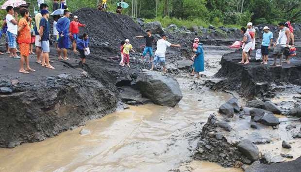 Residents pass a girl from an improvised bridge to avoid a river with lahar flow coming from Mayon volcano in Guinobatan, Albay province, south of Manila, yesterday.