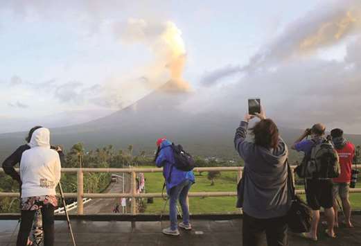 Visitors take pictures of volcanic ash spewing out of a crater of Mount Mayon volcano during an eruption in Camalig, Albay province, south of Manila, yesterday.