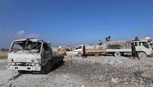 Syrian men unloading sacks of potatoes left on an abandoned truck following airstrikes by government forces which hit the vegetable market of Saraqeb in Syria's northwestern province of Idlib.