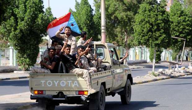 Southern Yemeni separatist fighters flash the V sign as they ride on the back of a truck in Aden.