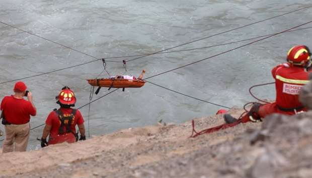 Rescue workers transport a victim after a bus crashed with a truck and careened off a cliff along a sharply curving highway north of Lima, Peru
