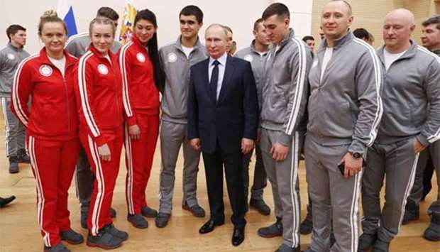 President Vladimir Putin poses with Russian athletes and team members who will take part in the 2018 Pyeongchang Winter Olympics, in Moscow on Wednesday.