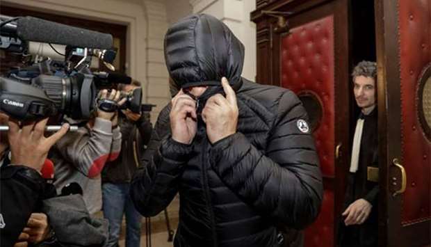 A man covers his face as he leaves the court during the first session of the 2013 Brussels Airport diamond heist case at the Brussels criminal court on Wednesday.