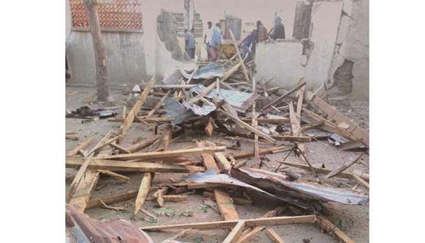 People stand near the damage following an attack on a mosque in the town of Gamboru in Borno state, Nigeria, yesterday.