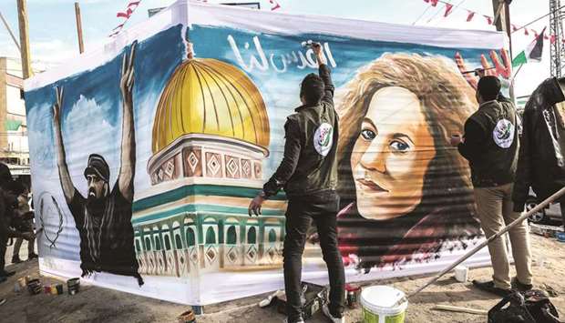 Palestinian artists paint a portrait of Ahed Tamimi (right), 16-year-old prominent campaigner against Israelu2019s occupation and who is currently detained, and Ibrahim Abu Thurayeh (left), who was shot dead in clashes between Israeli forces and protesters, along the border in December 2017, in Rafah in the southern Gaza Strip, yesterday.