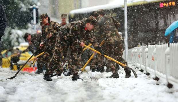 Chinese soldiers shovel snow to clear the road during a snowfall in Nanjing in China