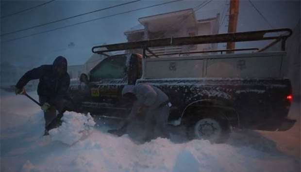 Two men shovel snow from under their truck that became stuck during a storm in Ocean City, Maryland on Thursday.