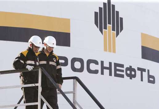 Workers stand next to a logo of Rosneft oil company at the central processing facility of the Rosneft-owned Priobskoye oil field outside the West Siberian city of  Nefteyugansk, Russia (file). Russia supplied 5.12mn tonnes of crude to China in November, official customs data show, the equivalent of about 1.3mn bpd.