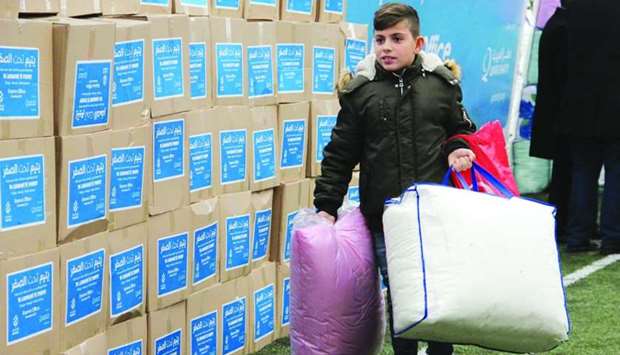 A young boy carries relief materials received from Qatar Charity.